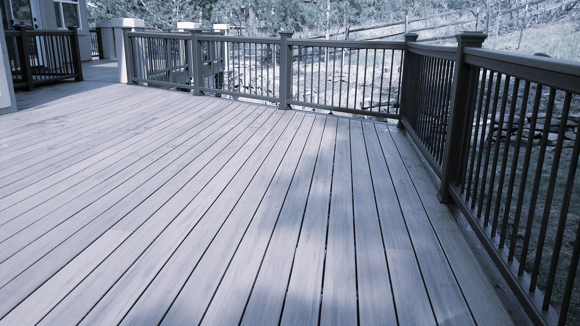 Large modern house with gray stone exterior and patterned driveway.