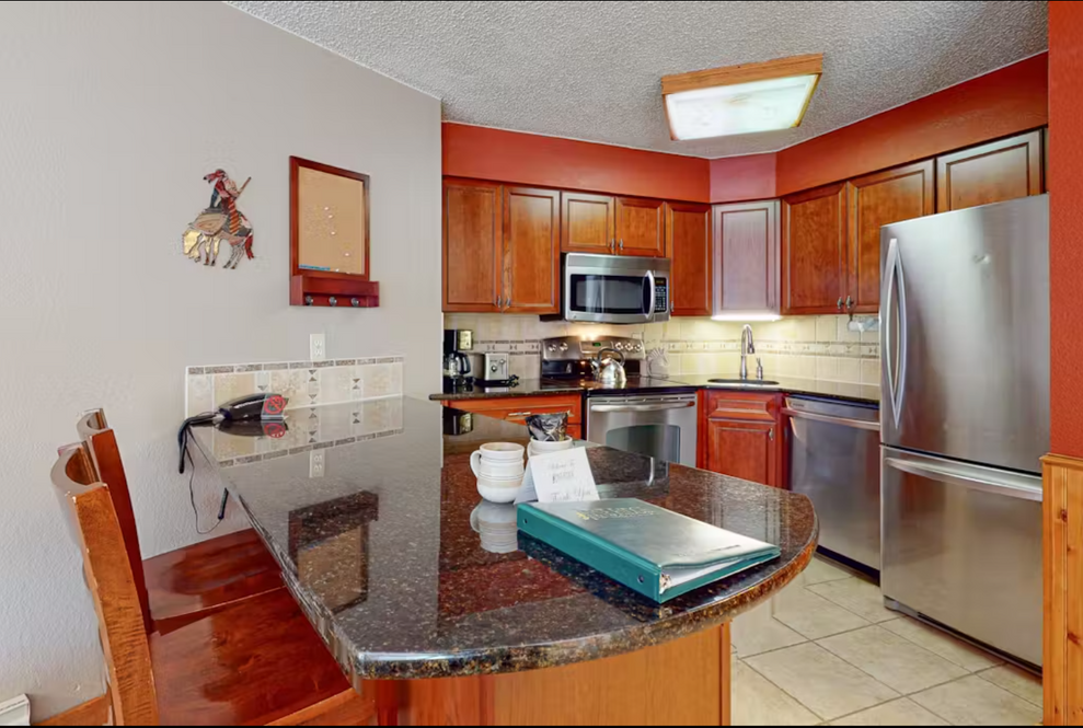 Kitchen with brown cabinets, stainless steel appliances, and a granite countertop island.