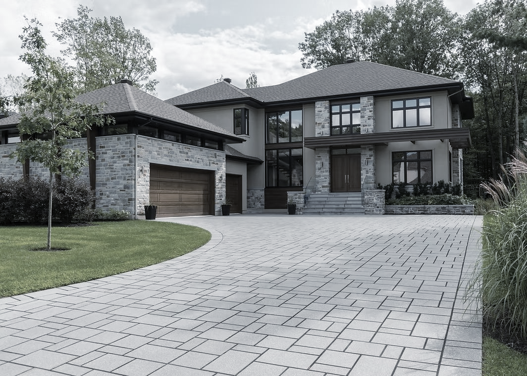 Gray stone and stucco house with driveway and trees.