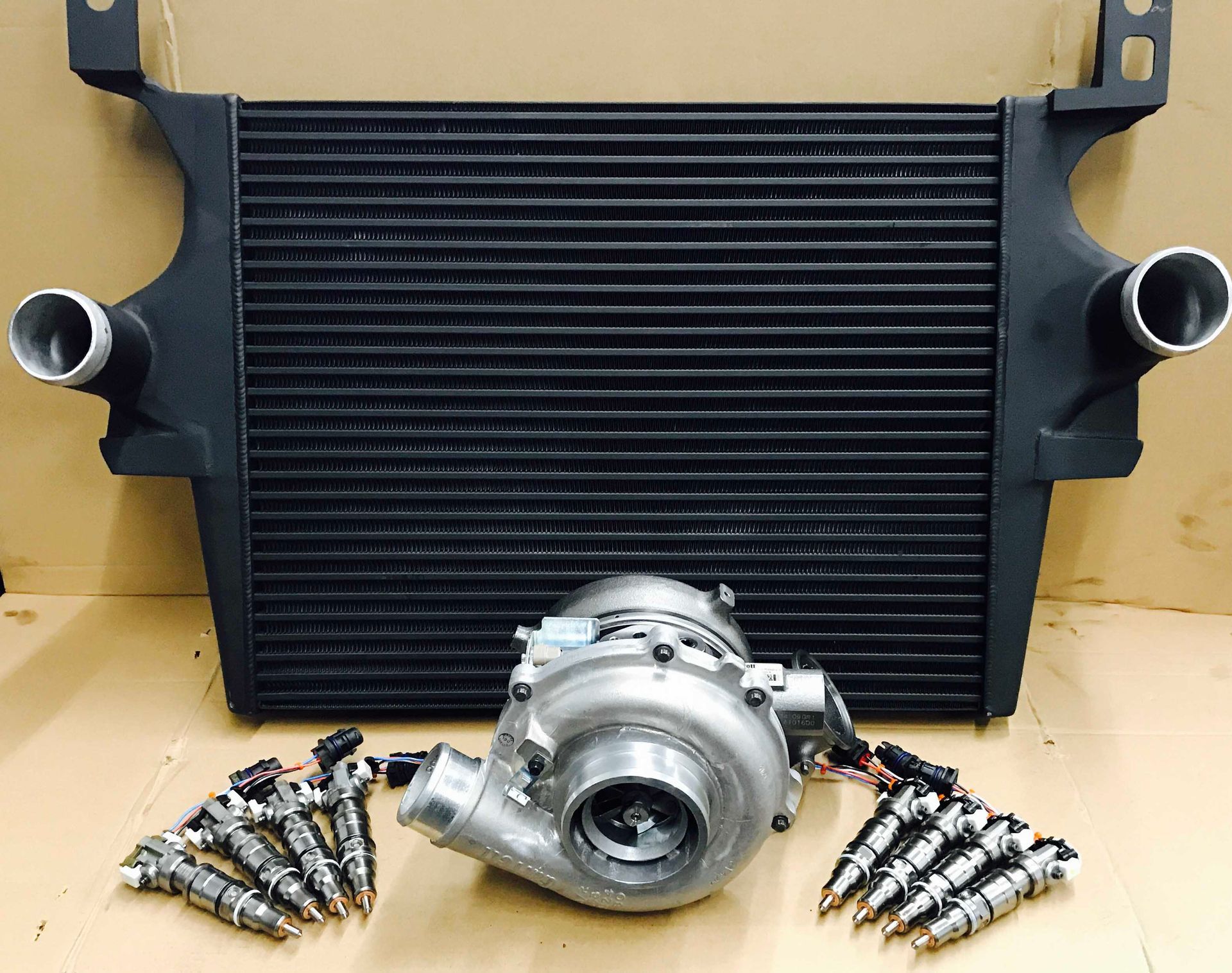 Black intercooler, turbocharger, and fuel injectors arranged on a surface.