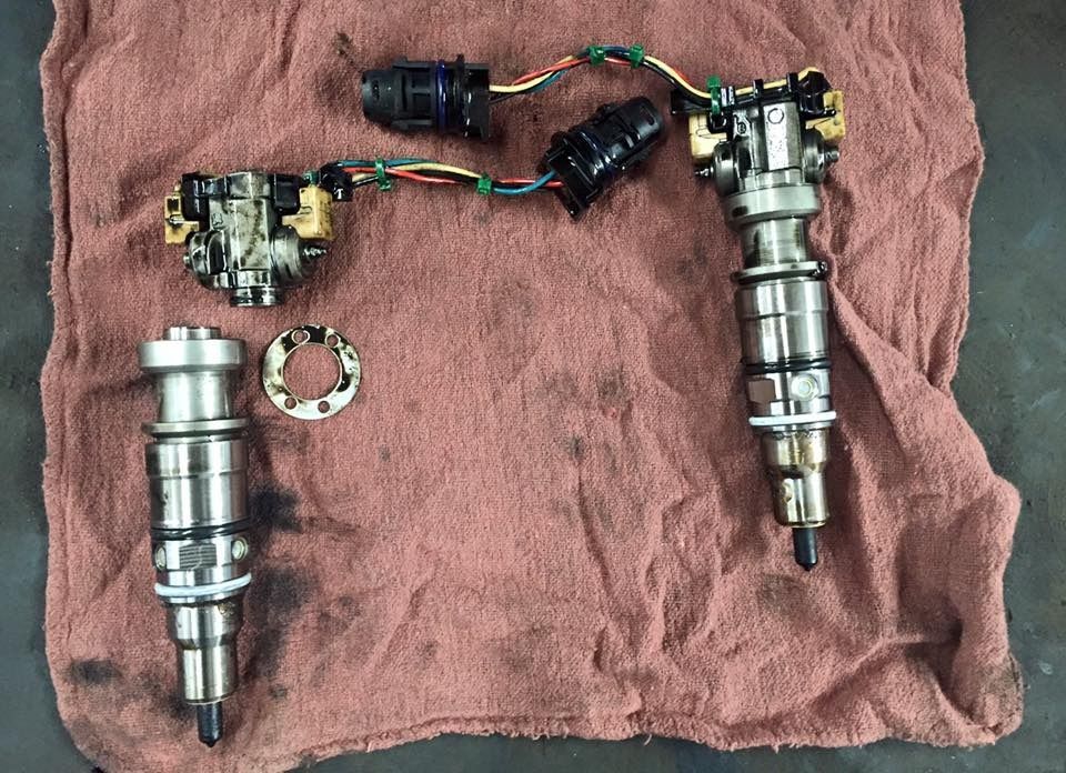 Diesel fuel injectors and related components laid out on a red cloth.