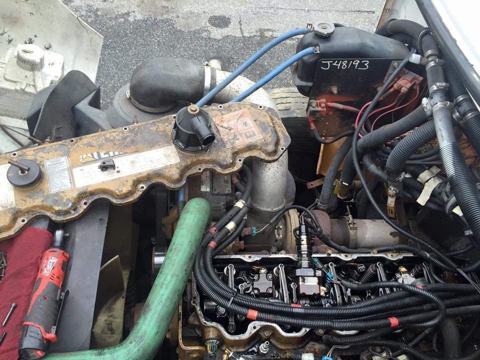 Overhead view of a truck engine with components exposed, including a valve cover, turbo, and hoses.