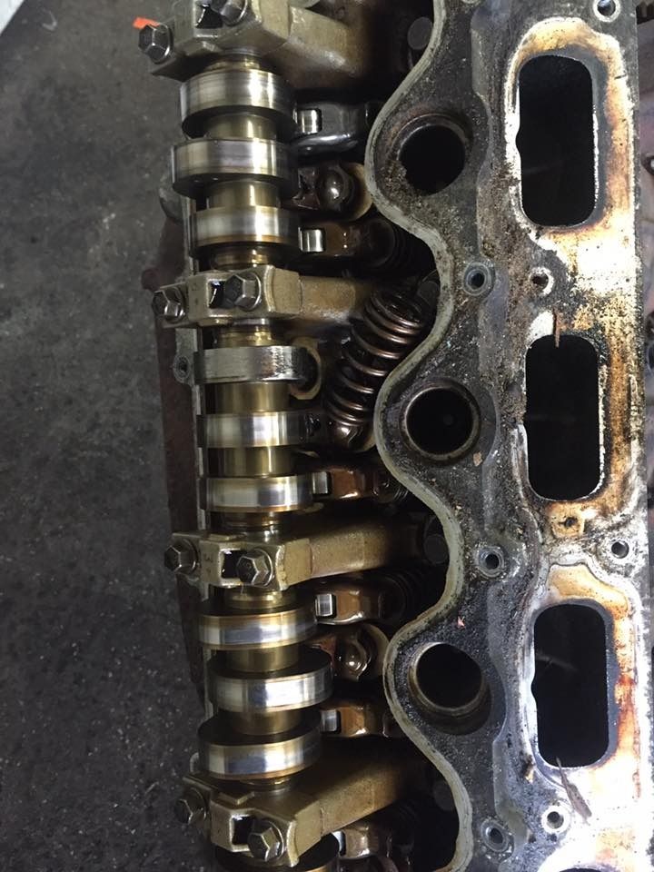 Engine cylinder head with camshaft, valves, and springs visible.
