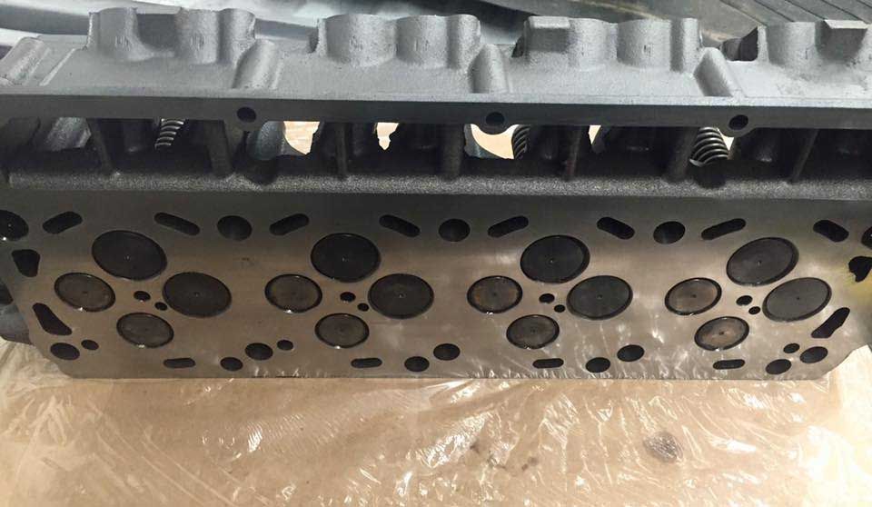 Engine cylinder head with multiple valve openings. Gray metal, close-up view.