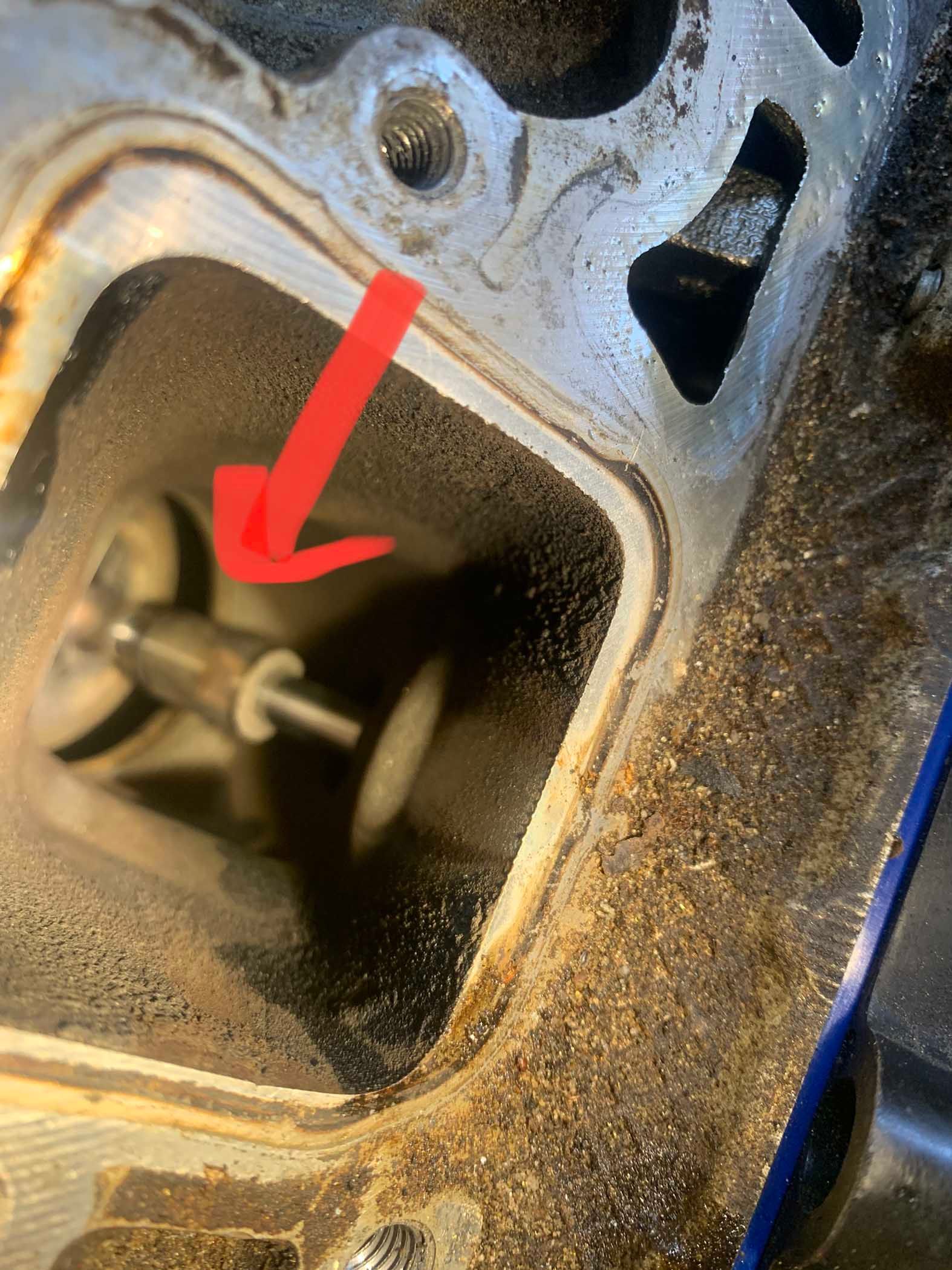 Close-up of engine valve in a cylinder head, indicated by a red arrow.