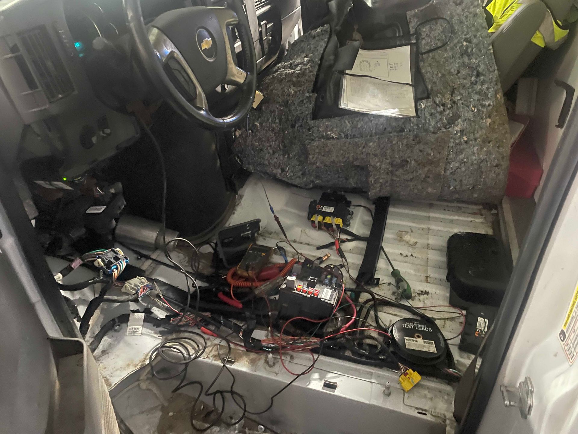 Interior of a damaged van with exposed wiring and missing floor components.
