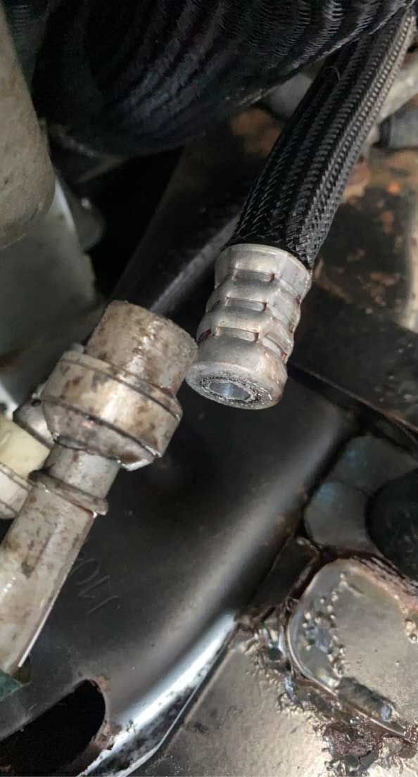 Close-up of car parts: metal tubes and a black braided hose, likely for fuel or fluid transport.