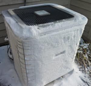 Snow-covered outdoor air conditioner unit with a black top grille