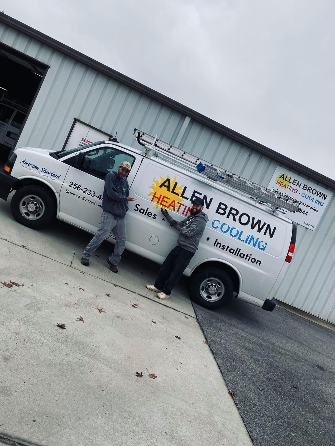 Two workers standing beside a white moving truck with open door outside a warehouse