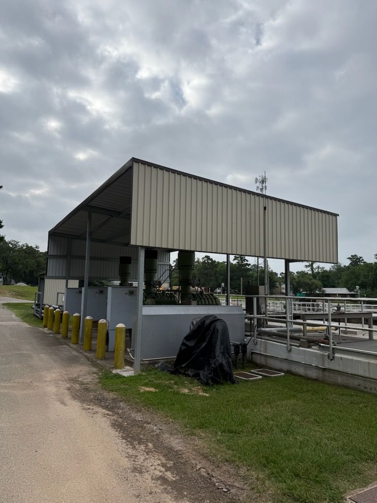 Open-sided farm shelter with metal roof beside a dirt road under cloudy skies