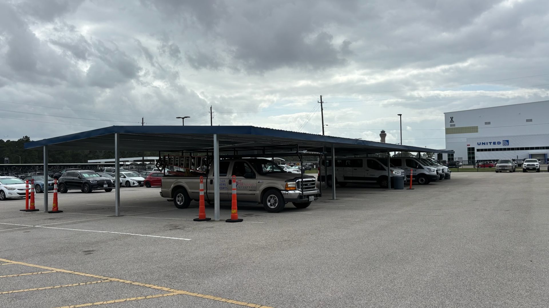Covered parking lot with cars and trucks under a cloudy sky