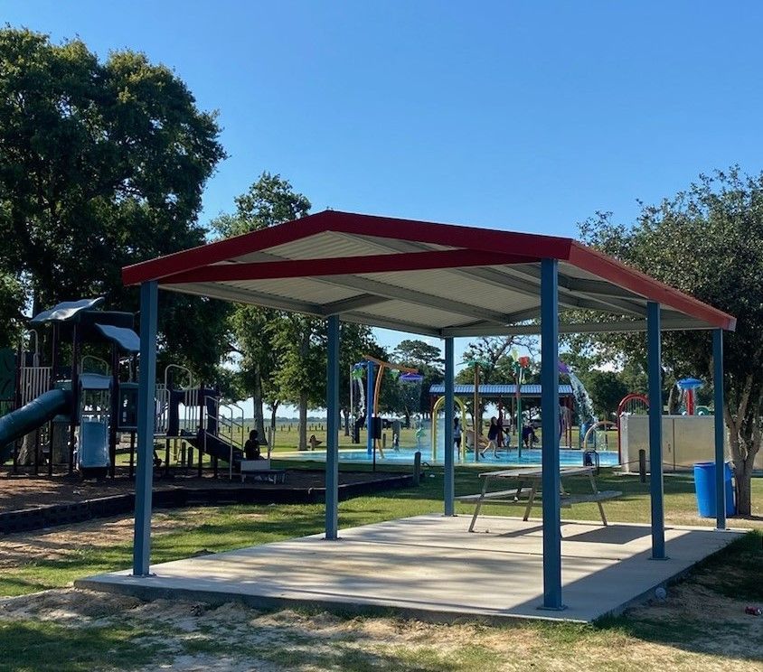 A picnic area with a red and white roof in a park