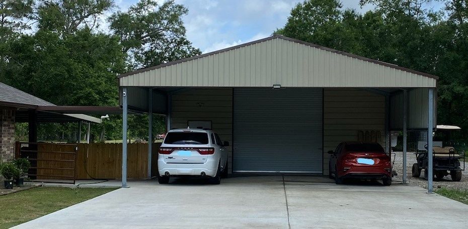Two cars are parked under a carport in front of a house.