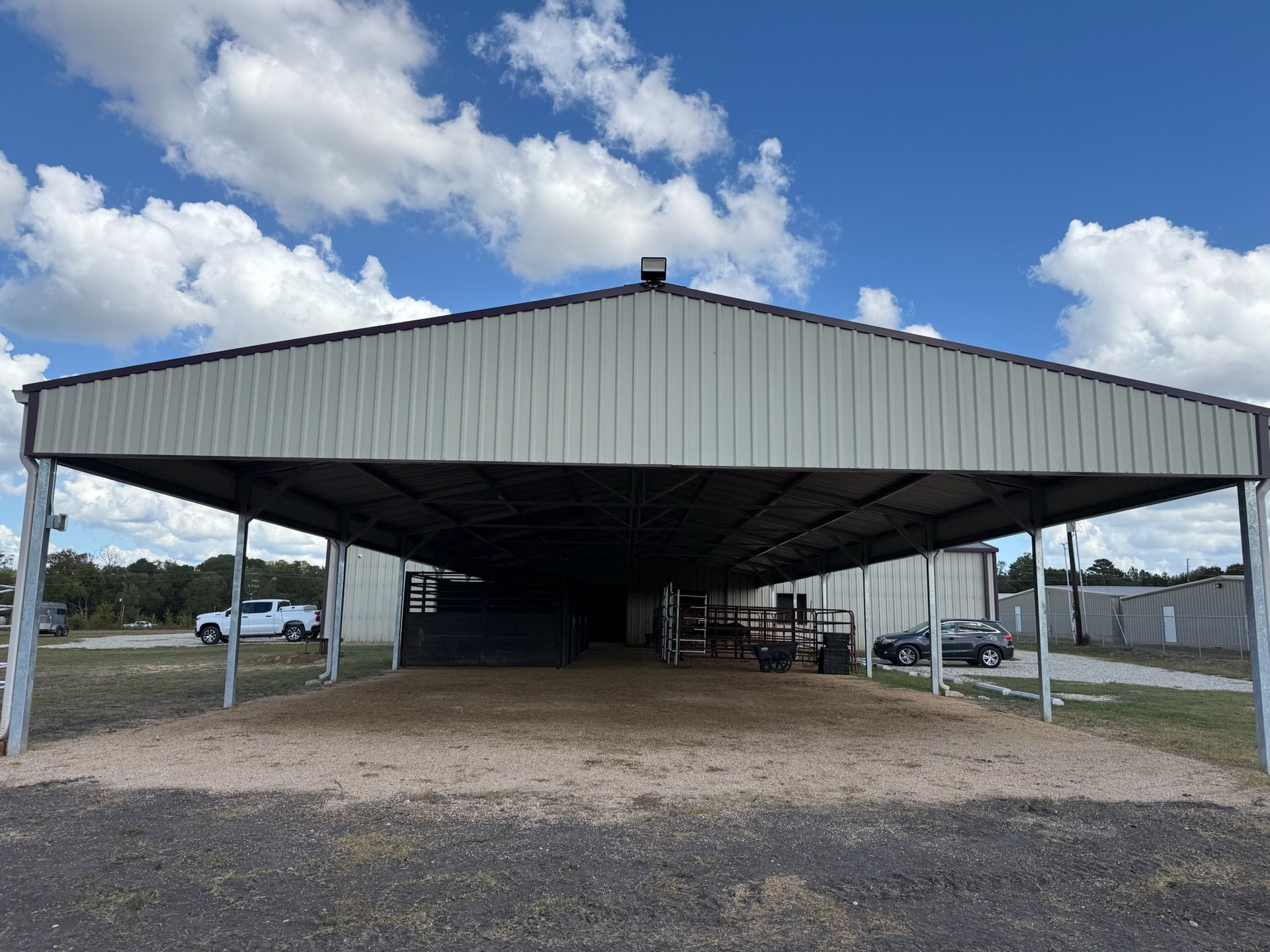 A large metal building with a covered parking lot in front of it.