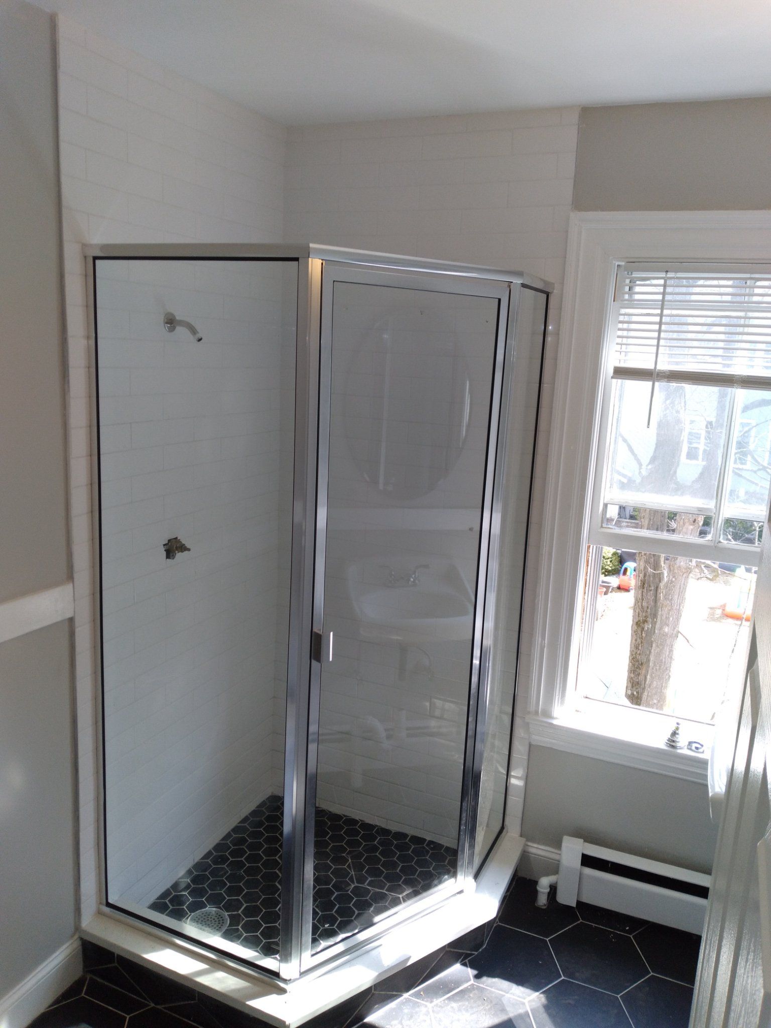A bathroom with a walk in shower and a window.