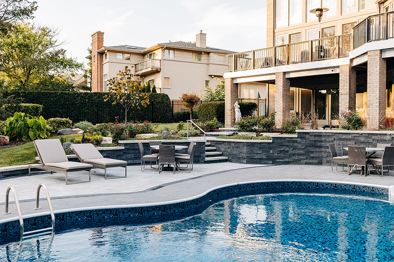 Backyard with pool, lounge chairs, and patio furniture; multi-story house in background.