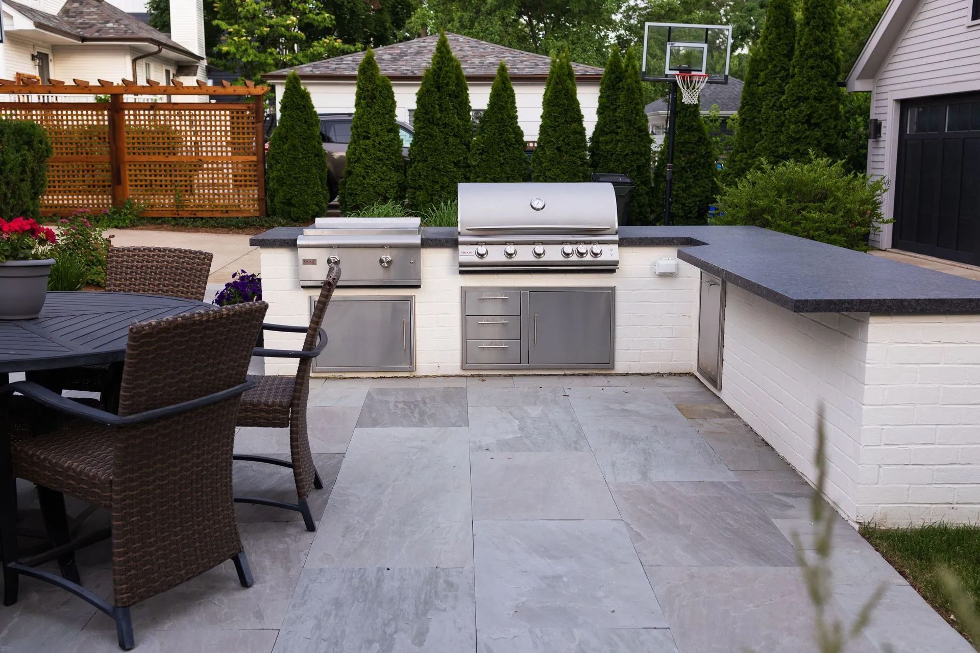 Outdoor kitchen with grill, counter, and patio seating.