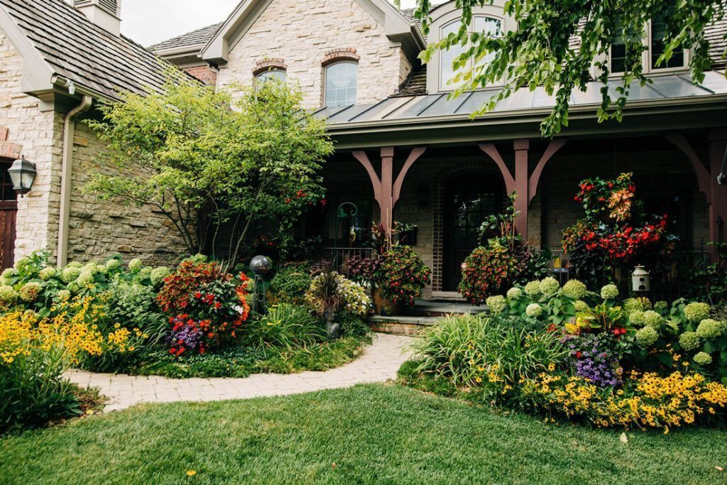Stone house with lush garden, curving path leading to a covered porch.