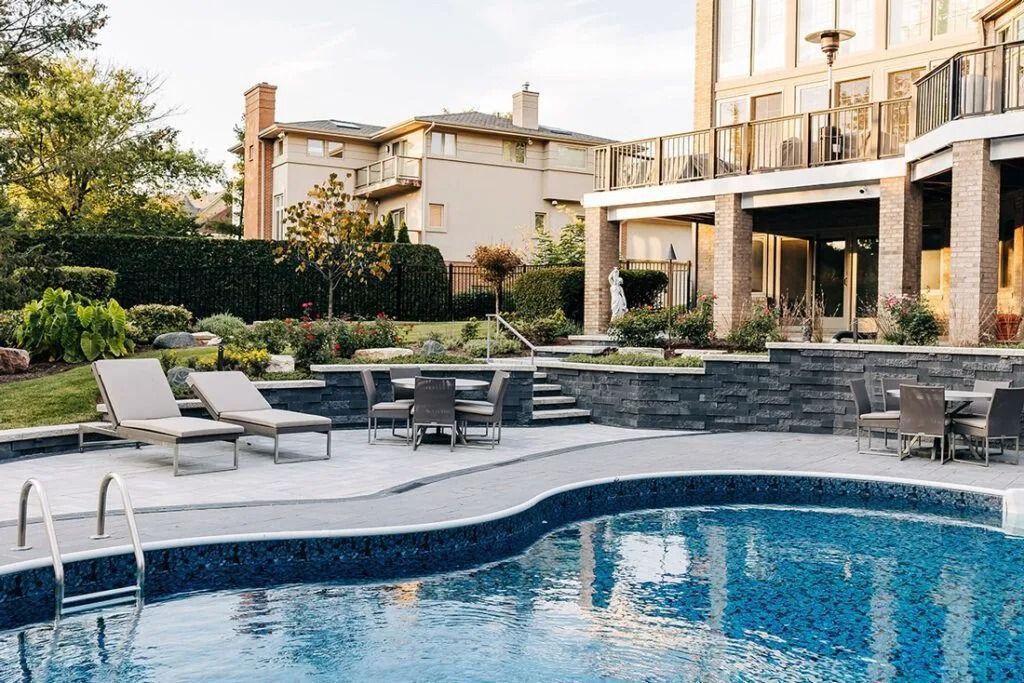 Swimming pool with lounge chairs and patio near a large building.
