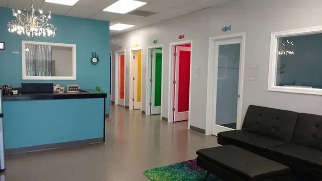 Reception area with blue walls, colorful doors, black sofa, and chandelier.