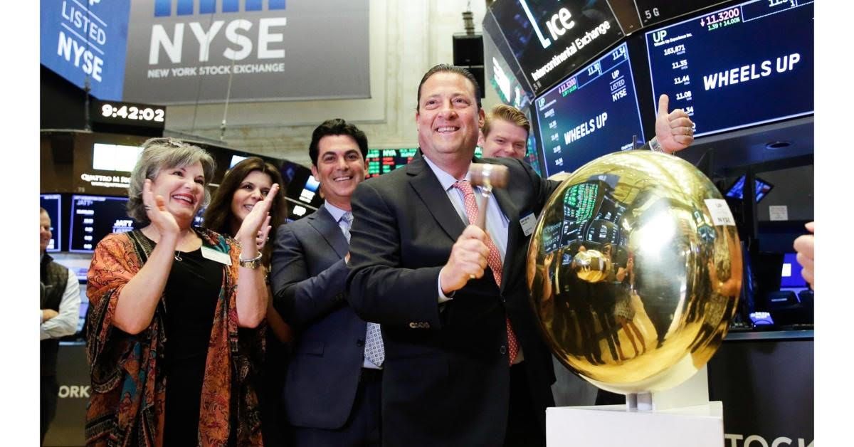 People at NYSE, man with gold ball, others celebrating. Blue screen, 