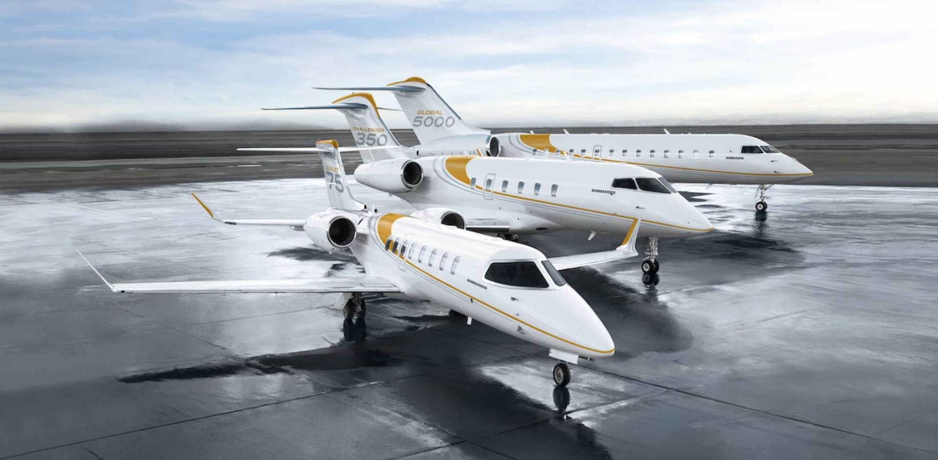 Three white private jets with gold accents parked on a wet tarmac.
