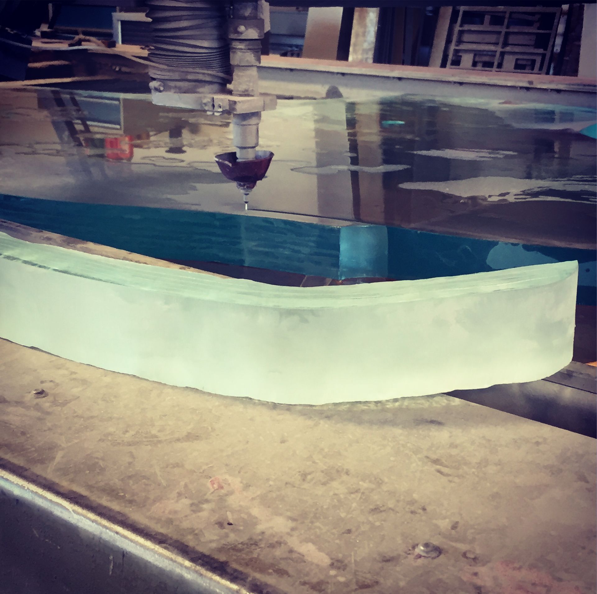 Water jet cutting curved glass, cutting bed with water.