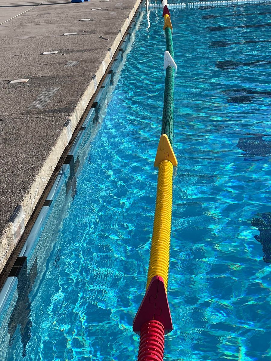 Yellow lane rope with red and white floats dividing a blue swimming pool from the deck