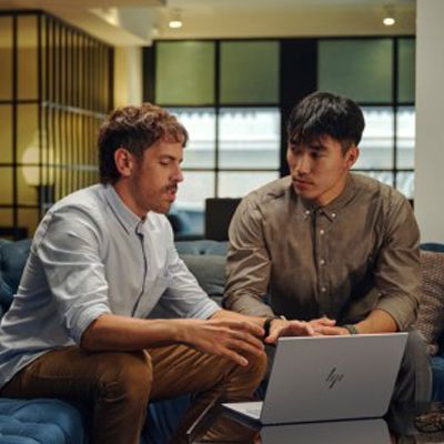 Two coworkers discussing over a laptop in a modern office lounge