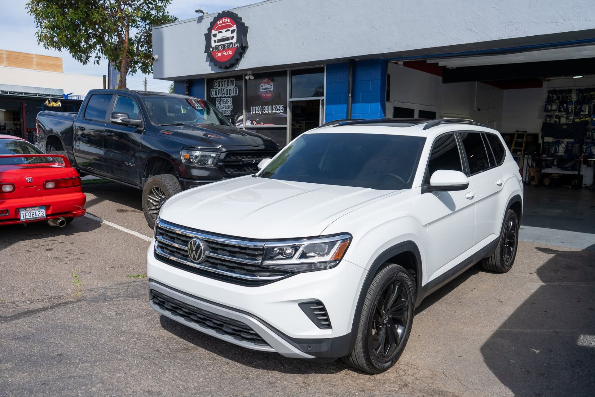 White SUV parked outside a car dealership, with other vehicles and a showroom in the background.