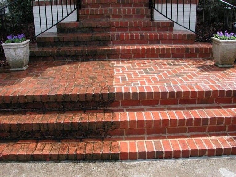 Brick front steps with red brick railings and potted flowers on either side