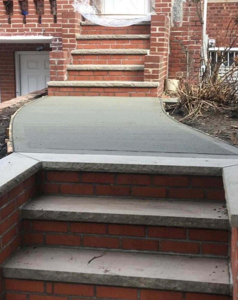 Brick steps leading to a raised concrete walkway beside a building entrance