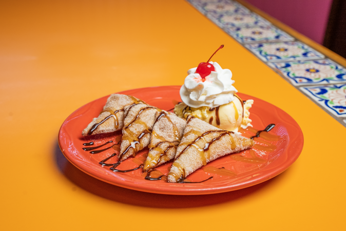 A plate of food with ice cream and a cherry on top on a table.