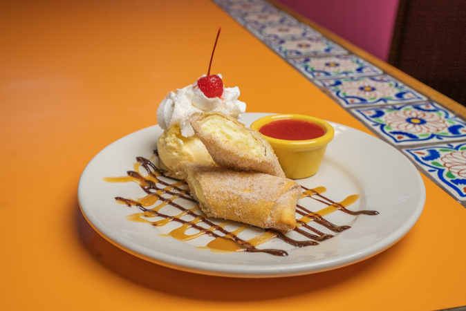 A white plate topped with a dessert with whipped cream and a cherry on top.