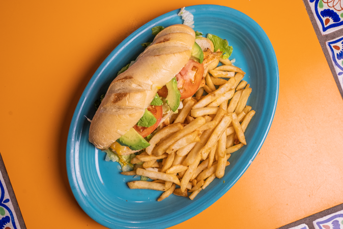 A sandwich and french fries on a blue plate on a table.