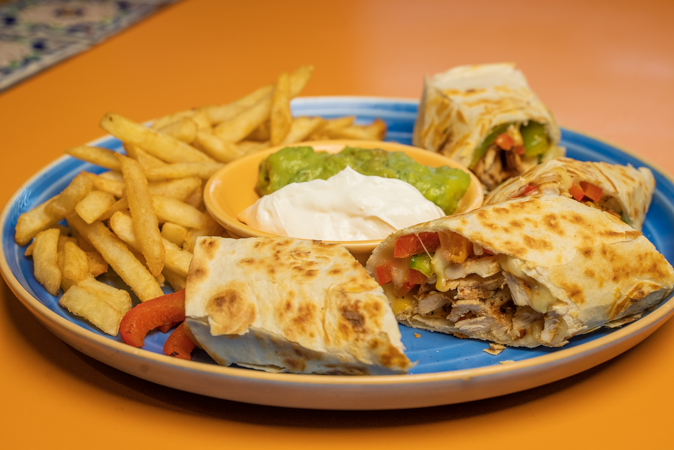 A plate of food with quesadillas and french fries on a table.