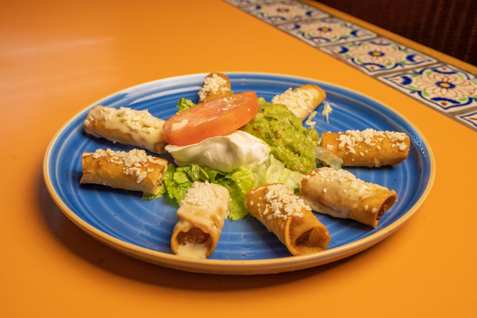 A blue plate topped with tacos and guacamole on a table.