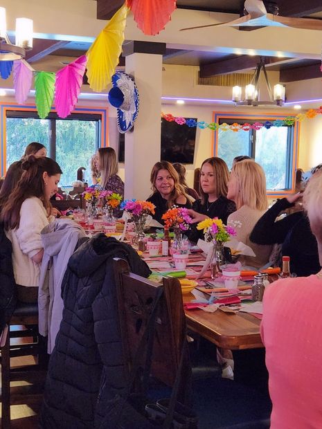 A group of people are sitting around a table with flowers on it