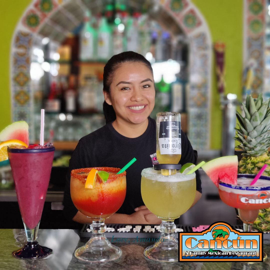 A woman sitting at a bar holding a corona beer.