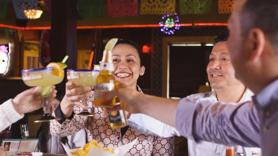 A group of people are toasting with drinks in a restaurant.