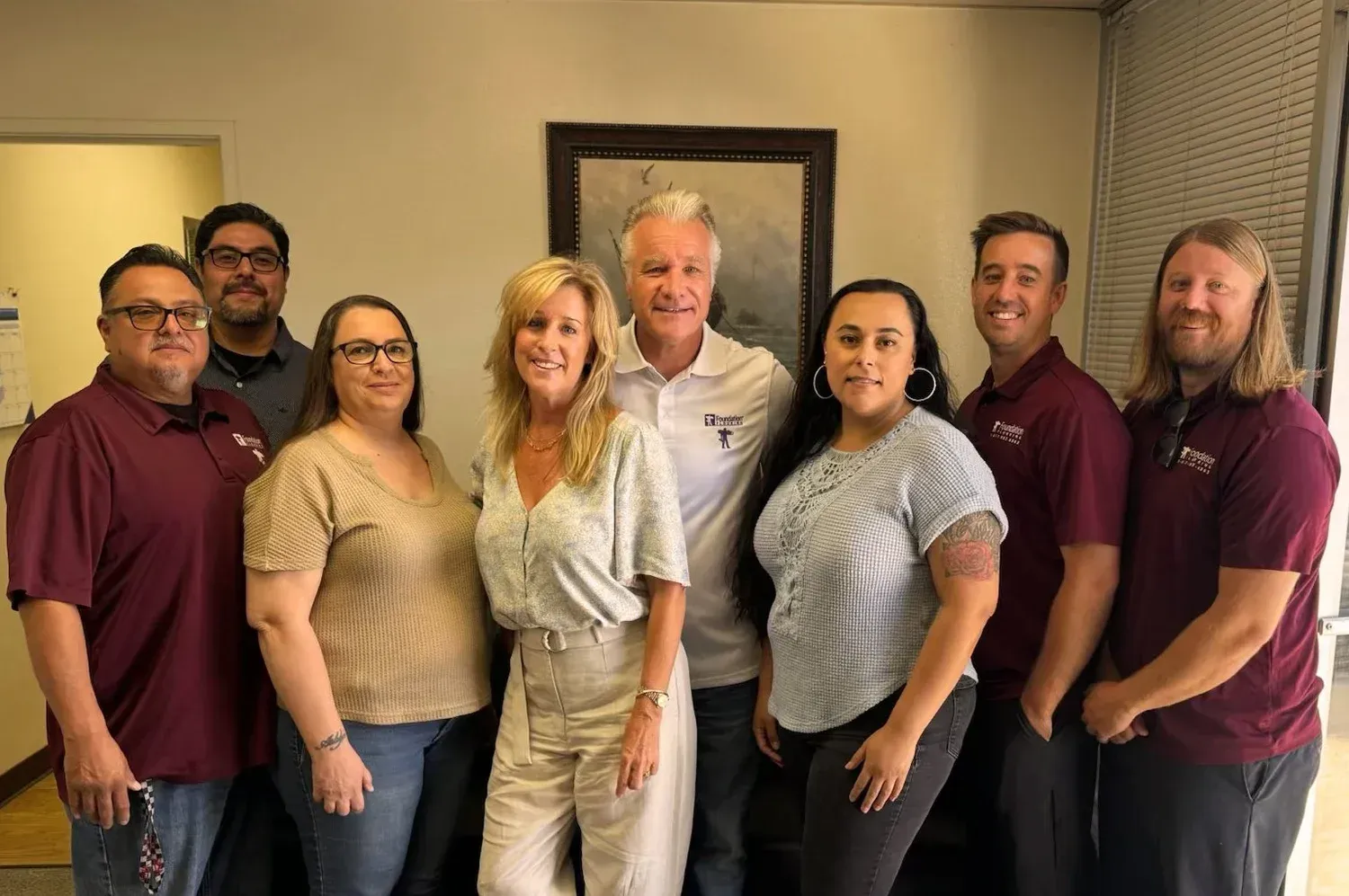Group of people in burgundy shirts posing for a photo, indoors.