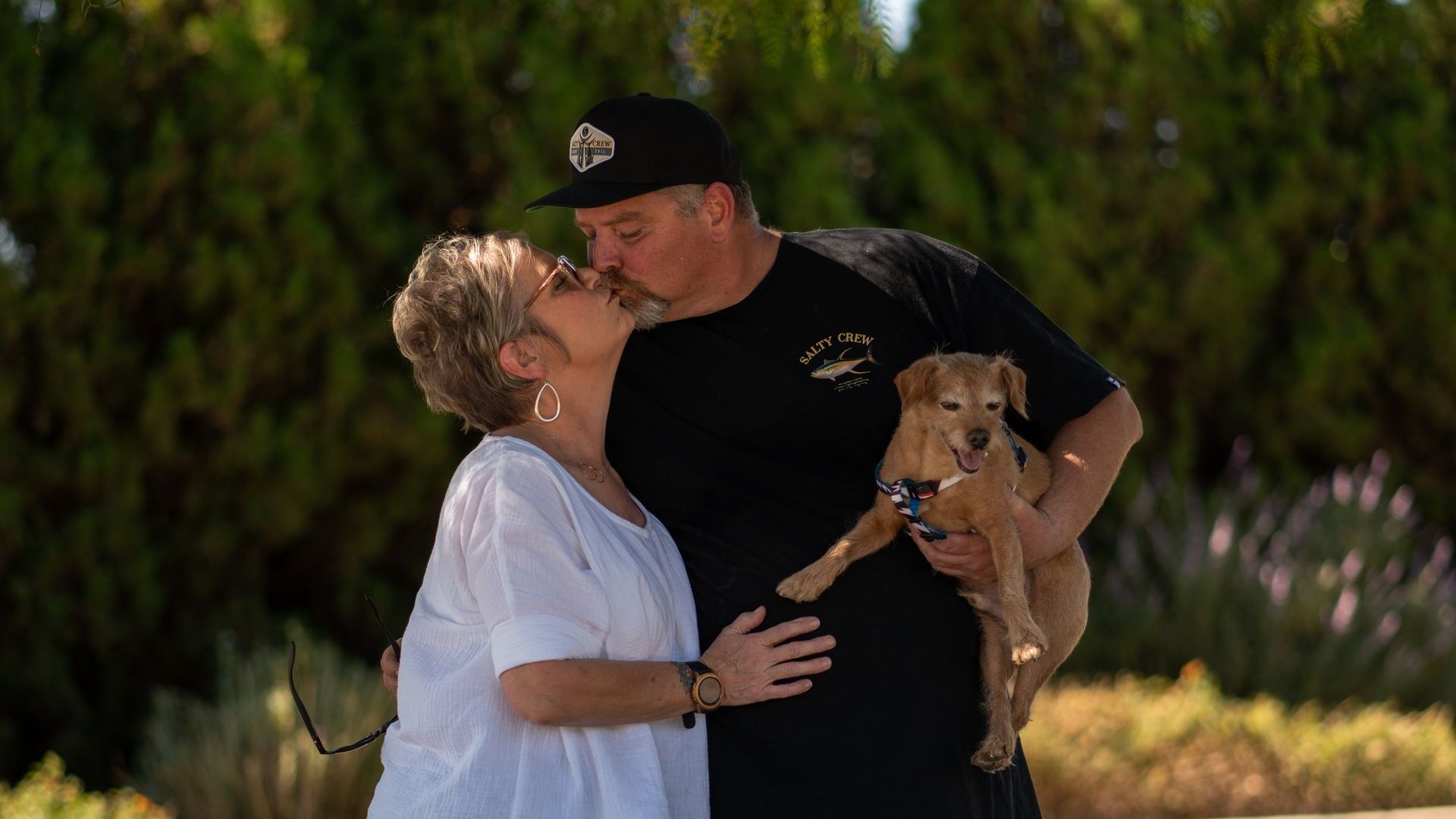 a couple holding a dog kissing