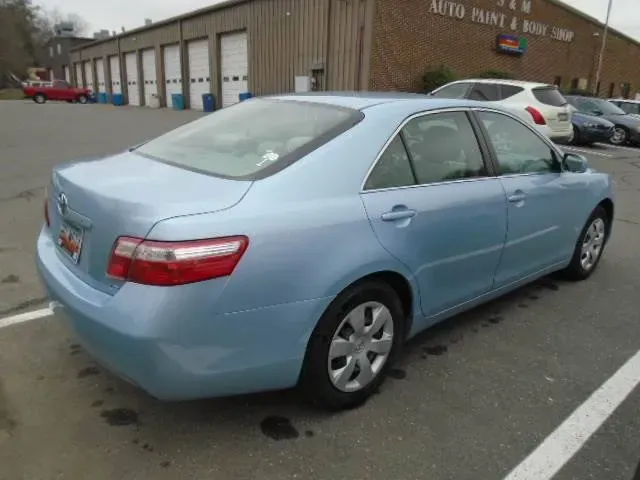 Light blue sedan parked outside an auto repair shop on a wet lot
