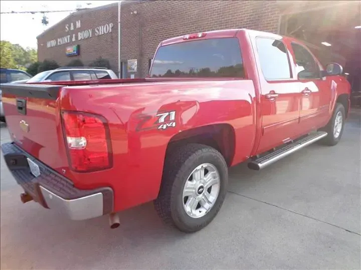 Red pickup truck parked outside a building, rear three-quarter view.