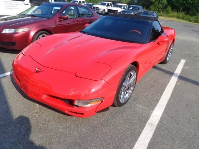 Red convertible sports car parked in a lot beside a maroon sedan.