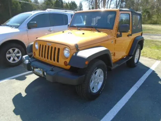Orange Jeep Wrangler parked in a lot beside a silver SUV