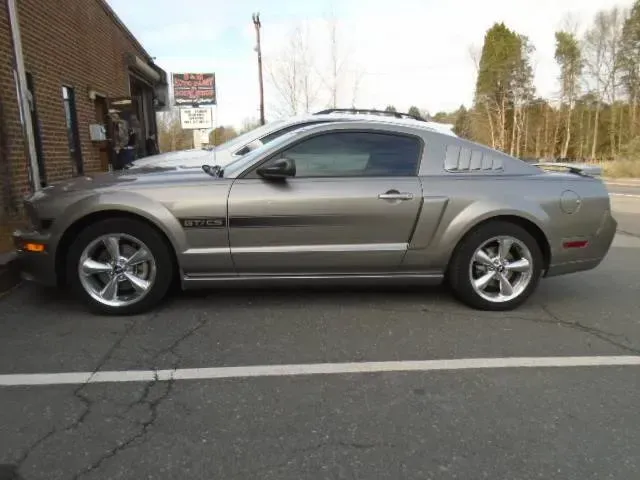 Gray sports coupe parked beside a brick building in a parking lot