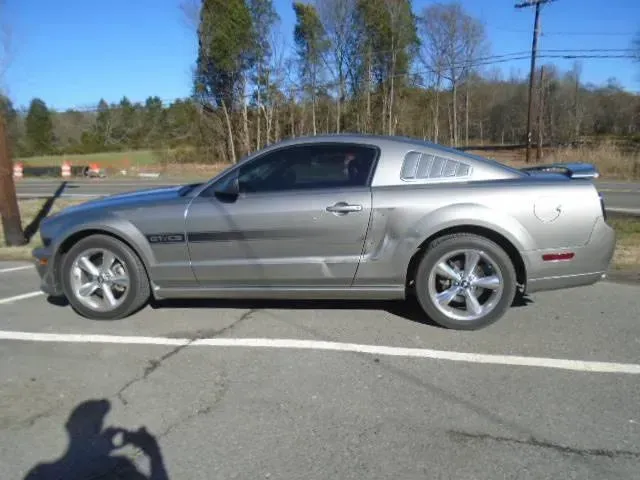 Silver sports car parked in an empty lot under a blue sky