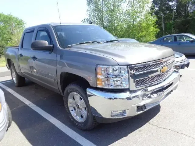 Silver pickup truck parked in a lot, front-left view on a sunny day.