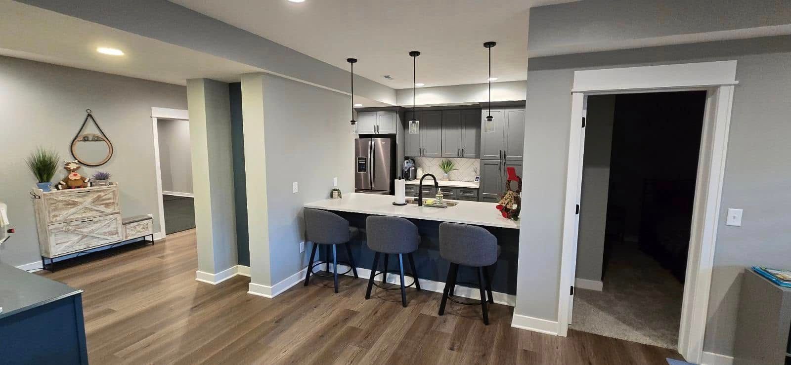 Modern kitchen with a breakfast bar, gray walls, and hardwood floors.